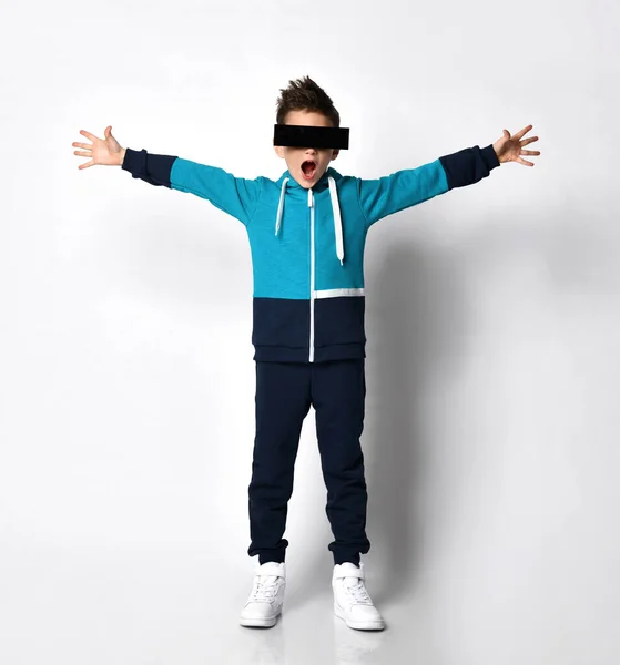 Spännande ung kille i en bekväm träningsoverall hoodie, klädd i augmented reality glasögon, mörka glasögon av ovanlig form — Stockfoto