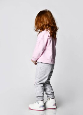 Pembe kazaklı, kızıl saçlı bir kızın, gri bir duvara karşı boş fotokopi odasına doğru yürüdüğünü hayal edin..