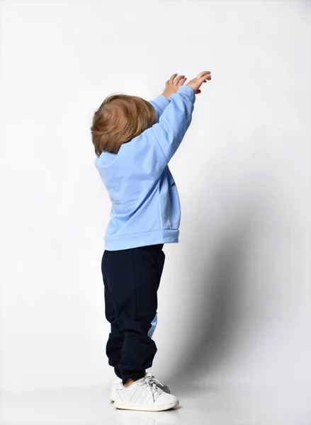 Blondynka mały chłopiec w niebieski t-shirt pozowanie na jasnym tle — Zdjęcie stockowe