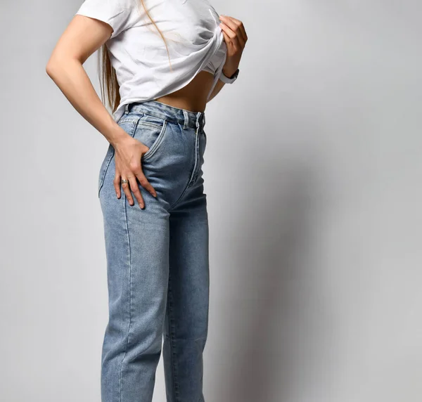 Okänd ung smal kvinna klädd i snygga blå jeans och vita sneakers. — Stockfoto