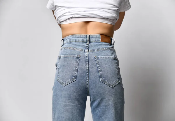 View from the back to the female ass in tight jeans with pockets of blue — Zdjęcie stockowe