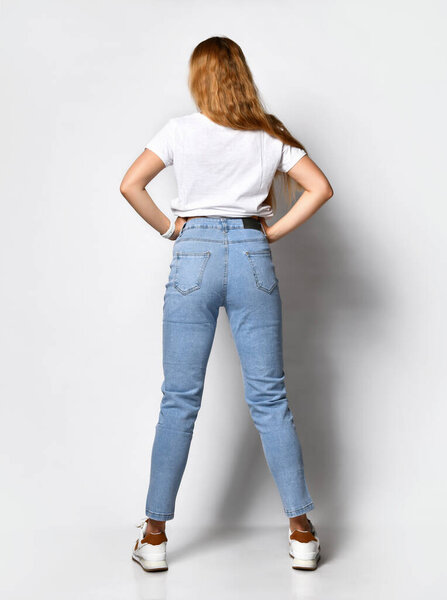 young skinny woman dressed in stylish blue jeans and white sneakers.