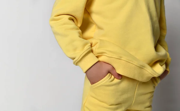 Vista de cerca de una parte de un cómodo traje casual para niños en un estilo deportivo, una sudadera con capucha de algodón amarillo suave y pantalones —  Fotos de Stock