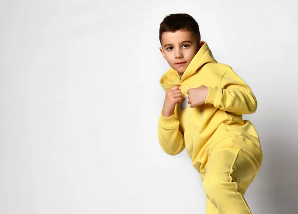 School age boy dressed in bright yellow sportswear kicks the camera. —  Fotos de Stock