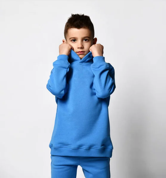 Studio portræt af en lille dreng i trendy blå sportsdragt på hvid baggrund. - Stock-foto