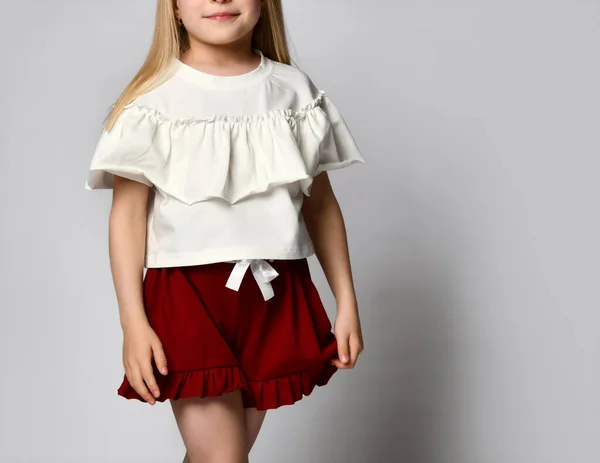 Τραβηγμένο πλάνο ενός μικρού κοριτσιού με φωτεινά καλοκαιρινά ρούχα. Το παιδί φοράει μια ελαφριά μπλούζα με βράκα και φωτεινό φαρδύ φούστα-σορτς. — Φωτογραφία Αρχείου
