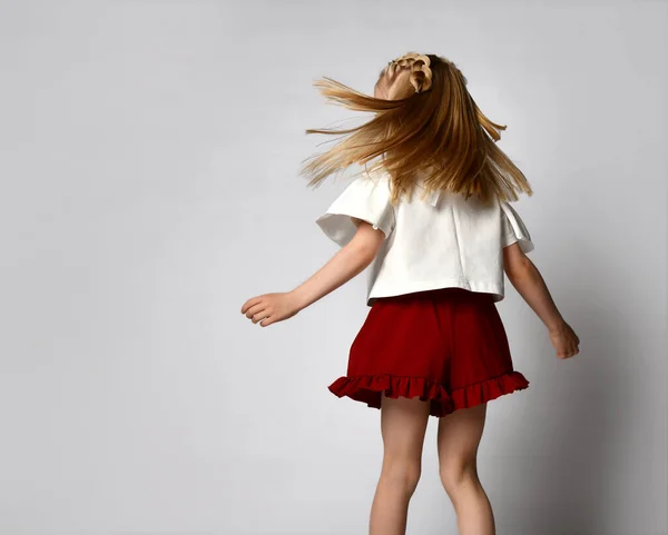 Menina loira irreconhecível dança e gira em um fundo branco. — Fotografia de Stock