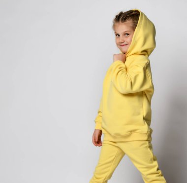 Beyaz arka planda sarı takım elbiseli şirin bir kızın stüdyo portresi..