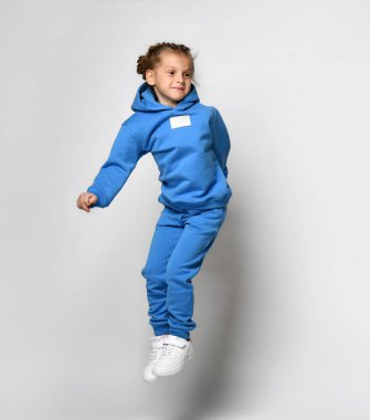 Şık, modern spor kapüşonlu neşeli kız ve pantolonu yüksekten atlıyor..