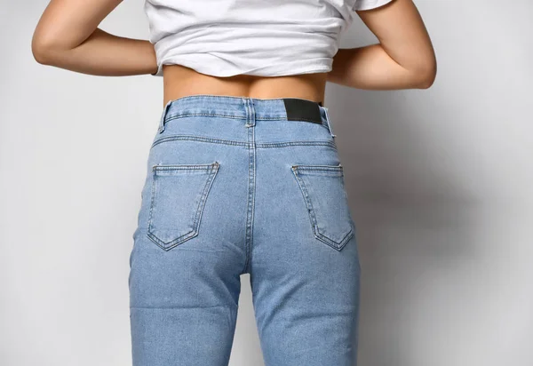 Modelo mostra jeans da parte de trás como eles se sentam no fundo. Jeans azul claro com bolsos. — Fotografia de Stock