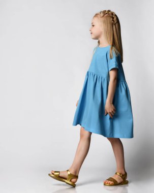 Beyaz arka planda mavi bir yaz elbisesi içinde güzel bir kızın stüdyo portresi..