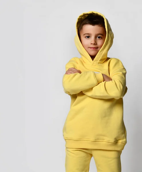 Studio portræt af en lille dreng i en trendy gul sportsdragt på hvid baggrund. - Stock-foto