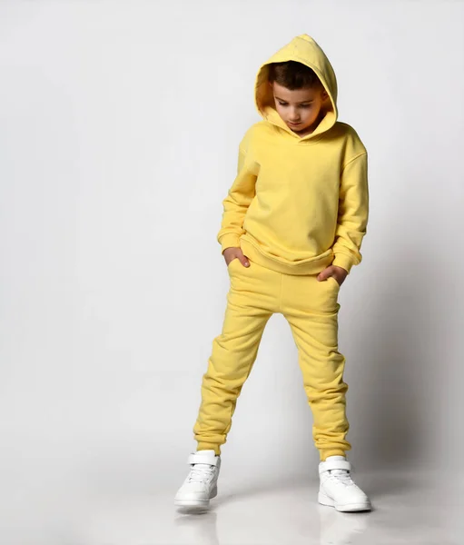 Niño de escuela en ropa deportiva de color amarillo brillante y zapatillas blancas sobre un fondo blanco. —  Fotos de Stock