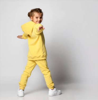 Eşofmanlı kadın uçan saç hareketleriyle dönüyor. Beyaz arkaplanda tam vücut uzunluğu izole edildi