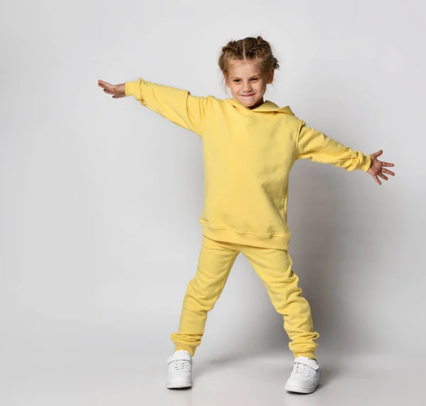 Parlak sarı spor takım elbiseli küçük bir kızın tam boy portresi.. — Stok fotoğraf