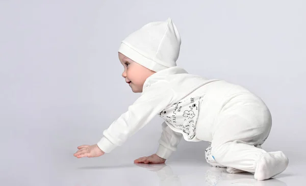 Side view of a pretty 10-month toddler crawling in the light bod — Stock Photo, Image