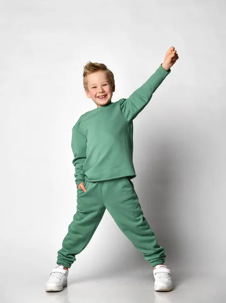 Lindo niño pequeño con la mano en el bolsillo y uno levantado bailando — Foto de Stock