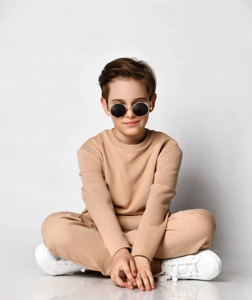 Cool niño preadolescente sentirse feliz sentándose en cuclillas sobre la pared del estudio —  Fotos de Stock