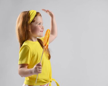 Gülümseyen kızıl saçlı kız lolipopları yalıyor.