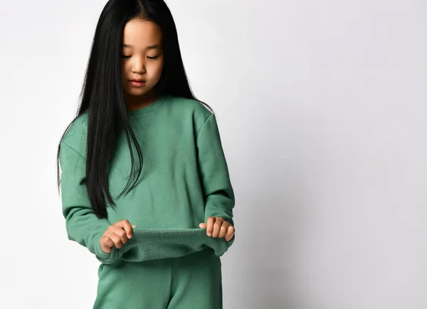 スタジオの背景を背景に、緑の暖かいスポーツウェアを披露アジアの女性の子供。流行の子供ファッション秋や春の服のためのスタイリッシュな広告. — ストック写真