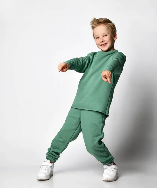 emotional portrait of Caucasian teenage boy in tracksuit. Surprised teenager looking at camera. Beautiful happy baby isolated on white background.