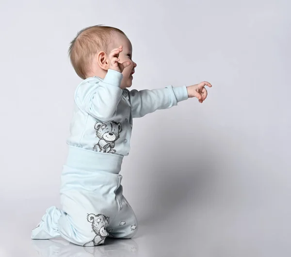 Side view of an adorable little baby baby Toddler smiling, He is in a cotton jumpsuit, points his finger in the direction of an empty seat — Stock Photo, Image