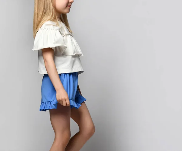 Vista lateral Cortada de una niña con ropa de verano brillante. El niño lleva una blusa ligera con calzones y pantalones cortos sueltos de color azul brillante. —  Fotos de Stock