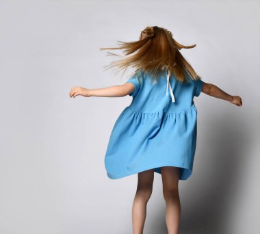 Tanımlanamayan küçük sarışın kız beyaz bir arka planda dans ediyor ve kıvranıyor..