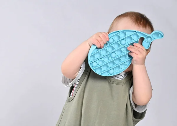 Curious little boy using toy pop it isolated on white background — Stock Photo, Image