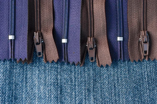 Pile of zippers on denim material — Stock Photo, Image