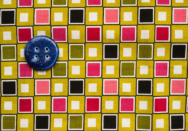 Sewing button on colourful fabric — Stock Photo, Image