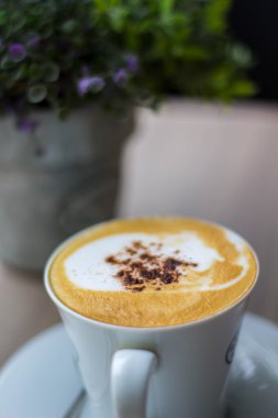 ahşap masa üzerinde beyaz bir plaka üzerinde beyaz bir fincan kapuçino