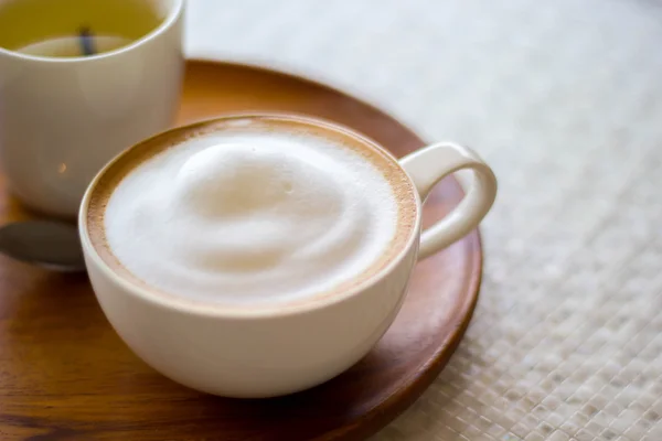 Cappuccino šálek bílá na bílé plotně na dřevěný stůl — Stock fotografie