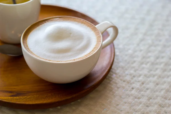 Cappuccino šálek bílá na bílé plotně na dřevěný stůl — Stock fotografie