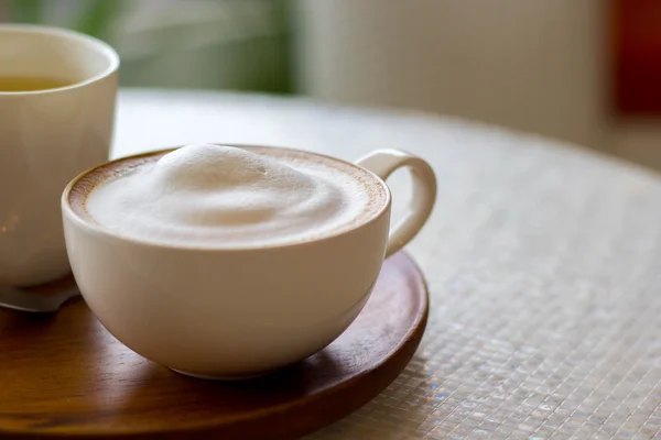 Cappuccino šálek bílá na bílé plotně na dřevěný stůl — Stock fotografie