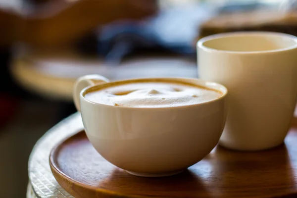 Cappuccino šálek bílá na bílé plotně na dřevěný stůl — Stock fotografie