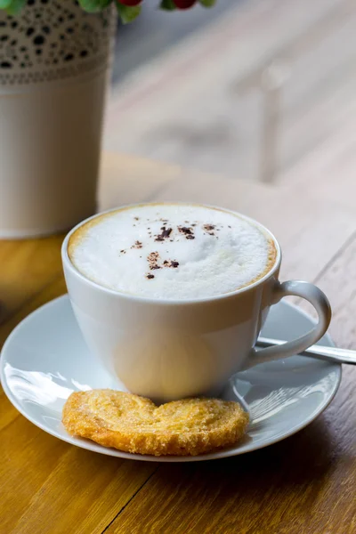 Cappuccino in a white cup on a white plate on wood table — Stock Photo, Image