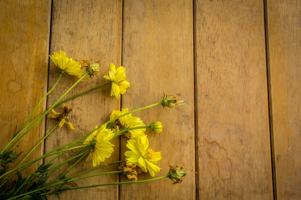 Fiori gialli posti su un tavolo di legno . — Foto Stock