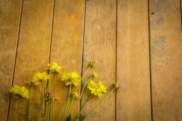 Flores amarelas colocadas em uma mesa de madeira . — Fotografia de Stock