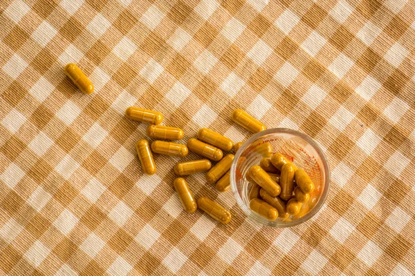 Copo de vidro de cápsulas de ervas medicinais em algodão . — Fotografia de Stock