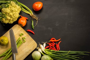 Young spring vegetables on black chalkboard from above. Backgrou