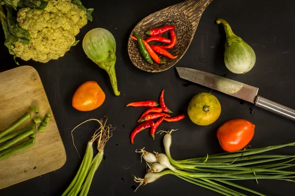 Young spring vegetables on black chalkboard from above. Backgrou
