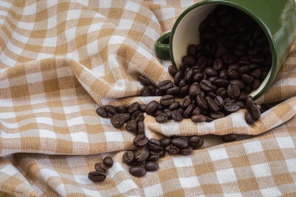 Cup full of coffee beans on cotton — Stock Photo, Image