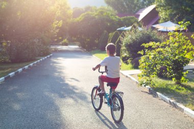 Harika bir yaz öğleden sonrasında bisikletli bir çocuk, güneş yerde bisikletli bir çocuğun gölgesini güzel bir şekilde çizer.