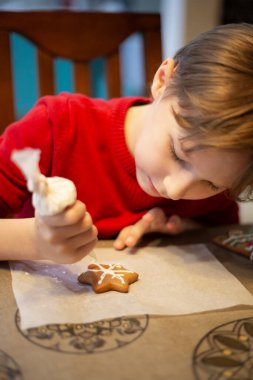 Mutfaktaki çocuk annemin Noel pastalarını ve kurabiyelerini süslemesine yardım ediyor.