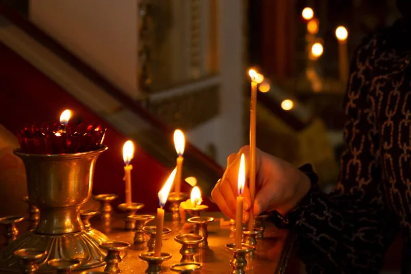 教会で灯されたろうそくを手に女性は聖人にろうそくを置きます — ストック写真