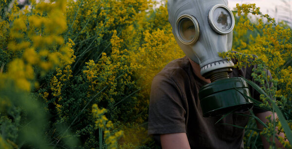 A man in a gas mask on a blooming meadow-protecting himself from allergies and viruses