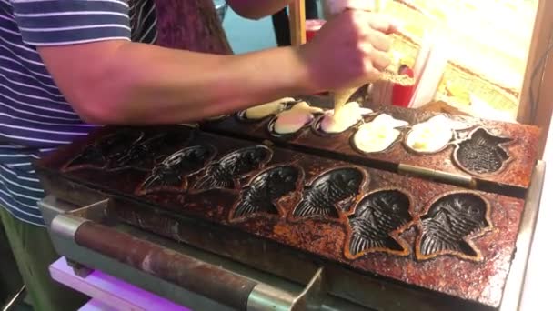 Cozinhar comida de rua. Taiyaki japonês bolo em forma de peixe preencher com pasta de feijão vermelho doce. Croissant Taiyaki sobremesa de lanche japonês em forma de peixe com feijão vermelho e creme — Vídeo de Stock