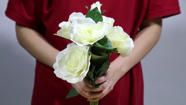 Közelíts női kezek kezében színes rózsa csokor. Női kéz megható rózsa bimbók levelek, fehér kötött pulóver háttér.