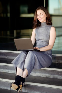 Bir modern ofis yapı içinde onun dizüstü bilgisayar kullanan iş kadını